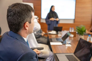 The team spirit and teamwork, professions and jobs for women, using a display screen for clearer explanations, ensuring a clear and comprehensive understanding of the work, discussion and understanding among employees, strategic plans to achieve goals, an Arab Gulf Emirati woman explaining work methods and professional development to a group of Arab and foreign individuals.