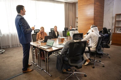 بيئة عمل إماراتية، توضيح اهداف وسياسة الشركة، الحوار والتفاهم بين الموظفين، الوحدة والعمل الجماعي، مهن ووظائف مكتبية، استخدام شاشة العرض لشرح اوضح، ضمان فهم واضح وشامل للاعمال، سيد اعمال اجنبي يناقش اساليب العمل والتطوير المهني داخل شركة امارتية