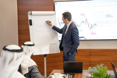 Writing on the board for clearer explanation, new partnership deals, Emirati work environment, dialogue and understanding among employees, unity and teamwork, professions and office jobs, ensuring a clear and comprehensive understanding of business, a foreign businessman discussing work methods and professional development within an Emirati company.