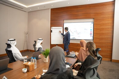 صفقات شراكة جديدة، بيئة عمل إماراتية، الحوار والتفاهم بين الموظفين، الوحدة والعمل الجماعي، مهن ووظائف مكتبية، استخدام شاشة العرض لشرح اوضح، ضمان فهم واضح وشامل للاعمال، سيد اعمال اجنبي يناقش اساليب العمل والتطوير المهني داخل شركة امارتية