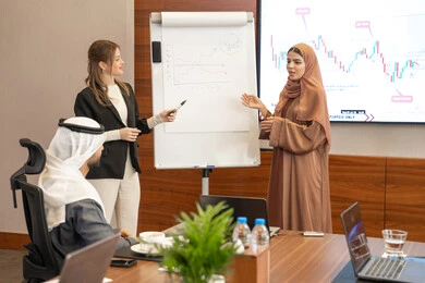 Expressions of self-confidence and seriousness, new partnership deals, an Emirati work environment, dialogue and understanding among employees, unity and teamwork, professions and office jobs, ensuring a clear and comprehensive understanding of business, a foreign businesswoman discussing work methods and professional development with an Emirati woman.
