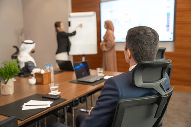 Learning work methods and professional development, new partnership deals, an Emirati work environment, dialogue and understanding among employees, unity and teamwork, office professions and jobs, ensuring a clear and comprehensive understanding of business, a foreign businesswoman discussing work methods and professional development with an Emirati woman.