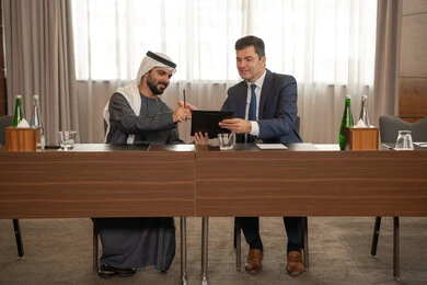 Electronic signature on new deals, Emirati work environment, study and analysis of new projects, dialogue and understanding between employees, unity and teamwork, professions and office jobs, ensuring a clear and comprehensive understanding of business, a foreign businessman in a business meeting inside an Emirati company with an Emirati Arab man.