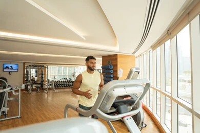 Burning calories and losing weight; a youthful activity that promotes physical fitness; the importance of exercise for building a strong body; an Emirati Gulf Arab man wearing sportswear exercises on a treadmill; adopting a healthy lifestyle.