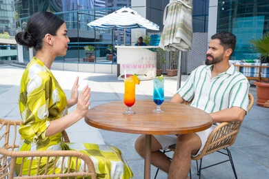 قضاء أجمل الأوقات في أفضل الفنادق, الإستجمام في الهواء الطلق, قضاء الأوقات العائلية المسلية, القيام بالأنشطة الترفيهية الممتعة في الإجازة, زوجان عربيان خليجيان إماراتيان يرتديان الزي الكاجوال يجلسان في إحدى المنتجعات في الإمارات و يتناولان المشروبات الباردة