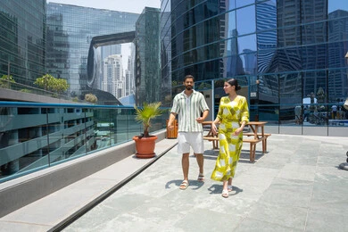 Walking along the edge of the swimming pool, an Emirati couple dressed casually enjoying a stroll; a happy family atmosphere; water sports activities; enjoying summer vacations; pleasant times at a tourist resort.