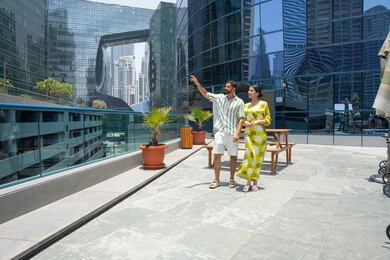 Spending summer vacation at tourist destinations, enjoying leisure time, fun recreational activities, walking along the edge of the swimming pool, an Emirati Gulf Arab couple wearing casual clothes and taking a stroll, with the husband pointing at something with his index finger.