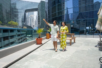 Enjoyable tourist holidays, leisure activities, fun and entertaining, walking along the edge of the swimming pool, an Emirati Gulf Arab couple wearing casual clothes and taking a stroll, with the husband pointing at something with his index finger.