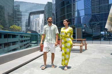 Enjoyable times at a tourist resort, walking along the edge of the swimming pool, an Emirati Gulf Arab couple in casual attire taking a stroll, a happy family atmosphere, water sports activities, and fun times during the holidays.