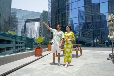 قضاء أوقات منعشة في فصل الصيف, الاشارة باصبع السبابة الى شئ ما, انشطة ترفيهية مائية, الاستمتاع بالرحلات الصيفية, قضاء الاوقات ممتعة، المشي على حدود بركة السباحة، زوجان عربيان خليجيان اماراتيان يرتديان اللبس الكاجوال و يقومان بالتنزه