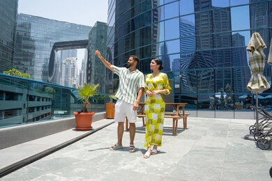 Changing the atmosphere at home, pointing at something with the index finger, water sports activities, enjoying summer trips, having fun, walking along the edge of the swimming pool, an Emirati Gulf Arab couple wearing casual clothes and taking a stroll