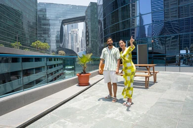 Tourism and enjoying the summer vacation, spending enjoyable times, walking by the pool, an Emirati Gulf Arab couple wearing casual clothes and taking a stroll, with the wife pointing at something with her index finger, outings and entertainment in a happy Emirati atmosphere.