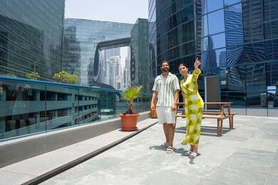 الاشارة باصبع السبابة الى شئ ما, انشطة ترفيهية مائية, الاستمتاع بالرحلات الصيفية, قضاء الاوقات ممتعة، المشي على حدود بركة السباحة، زوجان عربيان خليجيان اماراتيان يرتديان الزي الكاجوال و يقومان بالتنزه