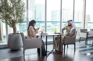 زميلان عمل عربيان خليجيان إماراتيان يجلسان على طاولة في أحد المطاعم الراقية في الإمارات يتبادلان الاحاديث والابتسامات،إيماءات السعادة والسرور، قضاء اوقات ممتعة مع الأصدقاء، بناء وتعزيز العلاقات والصداقات، مناقشة الاعمال وتبادل الافكار، اجتماع عمل في مكان خارج مقر الشركة