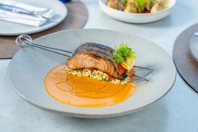 The art of etiquette and dining manners, seafood and healthy dishes, grilled salmon fillet with sauce and green vegetables, delicious meals, Arab Gulf Emirati restaurants, tasty and delicious recipes and dishes, presentation arts in restaurants and kitchens of the United Arab Emirates.