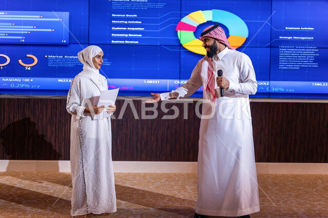 مذيع عربي خليجي سعودي يرحب بسيدة اعمال عربية خليجية سعودية في مؤتمر اقتصادي ، شرح الرسم البياني لسوق الاوراق المالية  ، الاستثمار والنمو الاقتصادي ،تحليل البيانات المالية ، متابعة الاسهم في البورصة ، التطور الاقتصادي السعودي