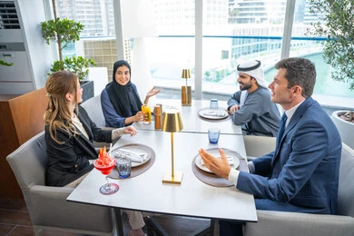 مشاركة الأوقات الممتعة, الاستمتاع بتناول المشروبات الباردة، اجتماع عمل في مكان خارج مقر الشركة, بناء علاقات اجتماعية ناجحة, مجموعة من الأصدقاء الاجانب والعرب خليجيين إماراتيين يجلسون على طاولة في إحدى المطاعم في الإمارات