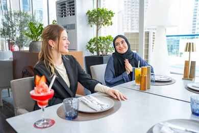 مشاركة الأوقات الممتعة, الاستمتاع بتناول المشروبات الباردة، اجتماع عمل في مكان خارج مقر الشركة, بناء علاقات اجتماعية ناجحة, مجموعة من الأصدقاء الاجانب والعرب خليجيين إماراتيين يجلسون على طاولة في إحدى المطاعم في الإمارات