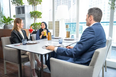 مشاركة الأوقات الممتعة, الاستمتاع بتناول المشروبات الباردة، اجتماع عمل في مكان خارج مقر الشركة, بناء علاقات اجتماعية ناجحة, مجموعة من الأصدقاء الاجانب والعرب خليجيين إماراتيين يجلسون على طاولة في إحدى المطاعم في الإمارات