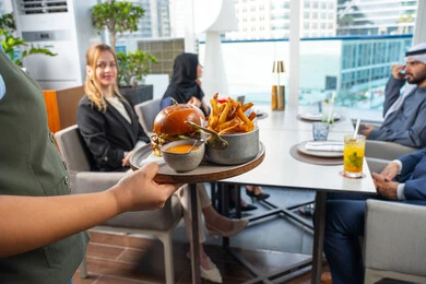 نادل يقدم الأطباق الغربية، خدمة في احدى المطاعم الأماراتية،اجتماع عمل في مكان خارج مقر الشركة,قضاء أوقات ممتعة مع الأصدقاء، جلسة وناسة وتعارف، مجموعة من الأصدقاء العرب الخليجين الاماراتيين يجلسون على المائدة في إحدى المطاعم في الإمارات، تناول الوجبات المفضلة