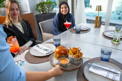 قضاء أوقات ممتعة مع الأصدقاء، خدمة في احدى المطاعم الأماراتية، نادل يقدم الأطباق الغربية، جلسة وناسة وتعارف، مجموعة من الأصدقاء العرب الخليجين الاماراتيين يجلسون على المائدة في إحدى المطاعم في الإمارات، تناول الوجبات المفضلة