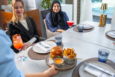 نادل يقدم الأطباق الغربية، خدمة في احدى المطاعم الأماراتية،اجتماع عمل في مكان خارج مقر الشركة,قضاء أوقات ممتعة مع الأصدقاء، جلسة وناسة وتعارف، مجموعة من الأصدقاء العرب الخليجين الاماراتيين يجلسون على المائدة في إحدى المطاعم في الإمارات، تناول الوجبات المفضلة