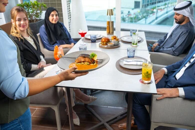 جلسة وناسة وتعارف، خدمة في احدى المطاعم الأماراتية، نادل يقدم الأطباق الغربية، اجتماع عمل في مكان خارج مقر الشركة,قضاء أوقات ممتعة مع الأصدقاء،  مجموعة من الأصدقاء العرب الخليجين الاماراتيين يجلسون على المائدة في إحدى المطاعم في الإمارات، تناول الوجبات المفضلة