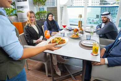 جلسة وناسة وتعارف، خدمة في احدى المطاعم الأماراتية، نادل يقدم الأطباق الغربية، اجتماع عمل في مكان خارج مقر الشركة,قضاء أوقات ممتعة مع الأصدقاء،  مجموعة من الأصدقاء العرب الخليجين الاماراتيين يجلسون على المائدة في إحدى المطاعم في الإمارات، تناول الوجبات المفضلة