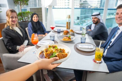 قضاء أوقات ممتعة مع الأصدقاء، جلسة وناسة وتعارف، خدمة في احدى المطاعم الأماراتية، نادل يقدم الأطباق الغربية، اجتماع عمل في مكان خارج مقر الشركة,مجموعة من الأصدقاء العرب الخليجين الاماراتيين يجلسون على المائدة في إحدى المطاعم في الإمارات، تناول الوجبات المفضلة