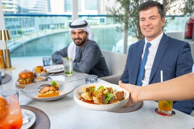 اجتماع عمل في مكان خارج مقر الشركة,قضاء أوقات ممتعة مع الأصدقاء، خدمة في احدى المطاعم الأماراتية، نادل يقدم الأطباق الغربية، جلسة وناسة وتعارف، مجموعة من الأصدقاء العرب الخليجين الاماراتيين يجلسون على المائدة في إحدى المطاعم في الإمارات، تناول الوجبات المفضلة