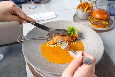 The art of etiquette and dining manners, seafood and healthy dishes, grilled salmon fillet with sauce and green vegetables, delicious meals, Arab Gulf Emirati restaurants, tasty and delicious recipes and dishes, presentation arts in restaurants and kitchens of the United Arab Emirates.