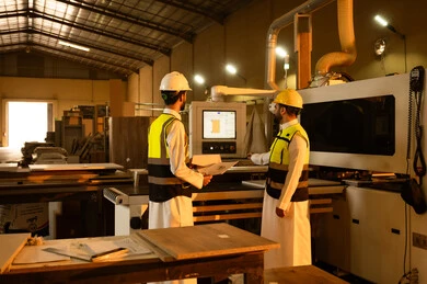 Supervising project progress, crafts and popular professions, purposeful dialogues and discussions, wooden furniture manufacturing workshop, carpentry workshops in Saudi Arabia, two Arab Gulf engineers from Saudi Arabia wearing safety vests and helmets standing inside the factory.