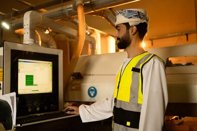 Management of devices through modern technologies, monitoring and supervising laboratory machines, wooden furniture manufacturing factory, industrial professions and jobs, carpentry workshops in the Sultanate of Oman, a side view of an Arab Gulf Omani engineer wearing a turban and safety vest standing inside the factory. Management of devices through modern technologies, monitoring and supervising laboratory machines, wooden furniture manufacturing factory, industrial professions and jobs, carpentry workshops in the Sultanate of Oman, a side view of an Arab Gulf Omani engineer wearing a turban and safety vest standing inside the factory.