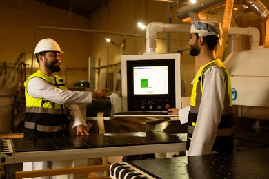 Recording the results of laboratory machine operations, popular crafts and manual trades, the concept of discussions and dialogues, a wooden furniture manufacturing workshop, two Arab Gulf engineers from Saudi Arabia wearing safety vests and helmets supervising the progress of the work plan.