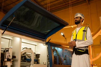 منتج محلي وطني، مهندس عربي خليجي عماني يرتدي العمامه وستره الحمايه يقوم بتفقد مخزن انتاج الخزائن الخشبيه داخل الورشه، مهن ووظائف صناعية، ورشات النجارة في سلطنه عمان