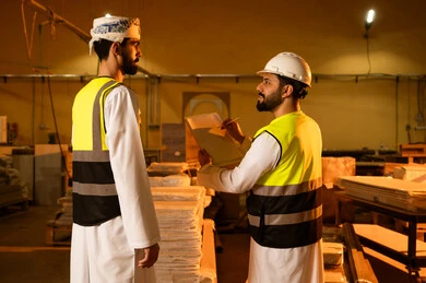 تسجيل وتوثيق الملاحظات، معمل تصنيع الأثاث الخشبي، مفهوم الناقشات والحوارات، مهندسان عربيان خليجيان سعوديان يرتديان سترة وخوذة الحماية يشرفان على سير خطة العمل، حرف ومهن يدوية شعبية، ورشات النجارة في المملكة العربية السعودية