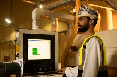 Monitoring the performance of industrial devices, controlling equipment using technology and techniques, wooden furniture manufacturing workshop, industrial professions and jobs, carpentry workshops in the Sultanate of Oman, a side view of an Arab Gulf Omani engineer wearing a turban and safety vest standing inside the factory. Monitoring the performance of industrial devices, controlling equipment using technology and techniques, wooden furniture manufacturing workshop, industrial professions and jobs, carpentry workshops in the Sultanate of Oman, a side view of an Arab Gulf Omani engineer wearing a turban and safety vest standing inside the factory.