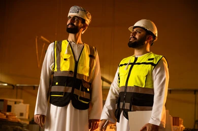 الإشراف على معدات المصنع، معمل تصنيع الأثاث المنزلي، التطور والتقدم التقني في صناعة الخشب، العمل في القطاع الصناعي, مهندسين عربيين خليجيين عمانيين يرتديان الخوذة وسترة الحماية يعملان في ورشة نجارة