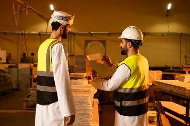 تسجيل وتدوين الملاحظات، التطور والتقدم التقني في صناعة الخشب، المتابعة والإشراف على آلات المعمل، العمل في القطاع الصناعي, مهندسين عربيين خليجيين عمانيين يرتديان الخوذة وسترة الحماية يعملان في ورشة نجارة, معمل تصنيع الأثاث المنزلي