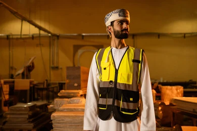 Supervising the progress of the work plan, workshops and traditional crafts, factories and workshops in the Sultanate of Oman, an Arab Gulf Omani engineer wearing a turban and protective vest is looking at something, a wood manufacturing workshop.