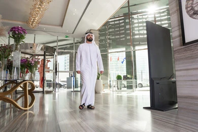 التقدم الى الامام، ايماءات تدل على الحركة والمشي، رجل عربي خليجي اماراتي يرتدي الكندورة و الغتره يقوم بالسير داخل الفندق، مفهوم السياحه و السفر