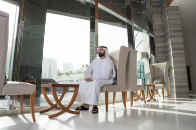Spending quiet time, the concept of relaxation and solitude, preparing to spend an enjoyable summer vacation, an Arab Gulf Emirati man wearing a kandura and ghutrah sitting in one of the luxury hotels.