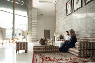 Sharing conversations and news, enjoying hot beverages, getting to know each other and building social relationships, the concept of a happy family, an Emirati couple in traditional attire sitting in a ground-level gathering, gestures of happiness and joy. Sharing conversations and news, enjoying hot beverages, getting to know each other and building social relationships, the concept of a happy family, an Emirati couple in traditional attire sitting in a ground-level gathering, gestures of happiness and joy.