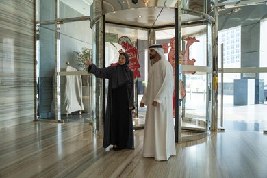 الاشارة الى شيء ما ، مفهوم الأسرة السعيدة، عطلة نهاية الأسبوع ، رحلة زوجية ممتعة ، قضاء أجمل الأوقات في أفضل الفنادق الخليجية، زوجان عربيان خليجيان اماراتيان يرتديان الزي التقليدي يقفان في بهو الفندق السياحي