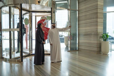 رحلة زوجية ممتعة ، قضاء أجمل الأوقات في أفضل الفنادق الخليجية، زوجان عربيان خليجيان اماراتيان يرتديان الزي التقليدي يقفان في بهو الفندق السياحي ، عطلة نهاية الأسبوع ، مفهوم الأسرة السعيدة، الاشارة الى شيء ما