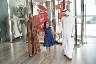 الاستمتاع في قضاء الوقت مع الأهل، عائلة عربيه خليجيه اماراتية ترتدي الزي التقليدي يسيرون داخل مدخل الاستقبال فى الفندق، الاستعداد لقضاء رحلة سياحية ممتعه مع العائلة، تبادل الاحاديث بتعابير السرور و السعادة