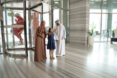 أجواء عائلية مبهجة، رجل عربي خليجي اماراتي يرتدي الكندورة و الدشداشة يقف برفقه زوجته و ابنته بايماءات السعادة و السرور ، الاشارة الى شيء ما، لحظات دخول عائلة عربية خليجية اماراتية إلى الفندق السياحي أجواء عائلية مبهجة، رجل عربي خليجي اماراتي يرتدي الكندورة و الدشداشة يقف برفقه زوجته و ابنته بايماءات السعادة و السرور ، الاشارة الى شيء ما، لحظات دخول عائلة عربية خليجية اماراتية إلى الفندق السياحي