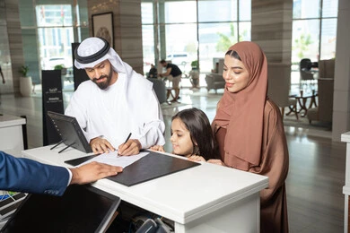 تعابير السعادة و السرور، عطلة نهاية الأسبوع، رجل اماراتي يرتدي الكندورة و الغتره يقف برفقة زوجته و ابنته عند مكتب الاستقبال فى احد الفنادق الفاخره يقوم بتأكيد حجزه داخل المنتجع تعابير السعادة و السرور، عطلة نهاية الأسبوع، رجل اماراتي يرتدي الكندورة و الغتره يقف برفقة زوجته و ابنته عند مكتب الاستقبال فى احد الفنادق الفاخره يقوم بتأكيد حجزه داخل المنتجع