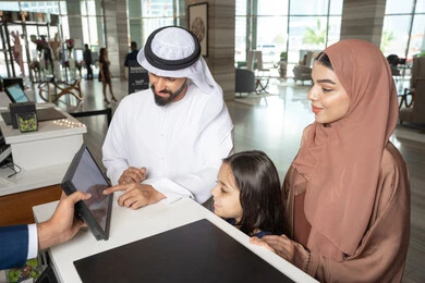 إتمام إجراءات الحجز في المنتجع باستخدام الجهاز اللوحي، الاستمتاع مع الأهل في عطلة نهاية الأسبوع, عائلة عربية خليجية اماراتية ترتدي الزي التقليدي تقف عند مكتب الاستقبال, الاستفسار حول خدمة العملاء, مفهوم الأسرة السعيدة, أهمية الترابط الأسري إتمام إجراءات الحجز في المنتجع باستخدام الجهاز اللوحي، الاستمتاع مع الأهل في عطلة نهاية الأسبوع, عائلة عربية خليجية اماراتية ترتدي الزي التقليدي تقف عند مكتب الاستقبال, الاستفسار حول خدمة العملاء, مفهوم الأسرة السعيدة, أهمية الترابط الأسري