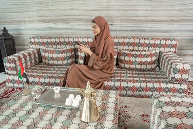 تعابير وإيماءات الفرح والسرور، متابعة أخبار وسائل التواصل الاجتماعي باستخدام الجوال، إمرأة عربية خليجية اماراتية مبتسمة ترتدي حجاب وعباءة تجلس في مجلس ارضي شعبي تمسك بيديها الهاتف المحمول، الدردشة والتواصل مع التواصل مع الأصدقاء أونلاين تعابير وإيماءات الفرح والسرور، متابعة أخبار وسائل التواصل الاجتماعي باستخدام الجوال، إمرأة عربية خليجية اماراتية مبتسمة ترتدي حجاب وعباءة تجلس في مجلس ارضي شعبي تمسك بيديها الهاتف المحمول، الدردشة والتواصل مع التواصل مع الأصدقاء أونلاين